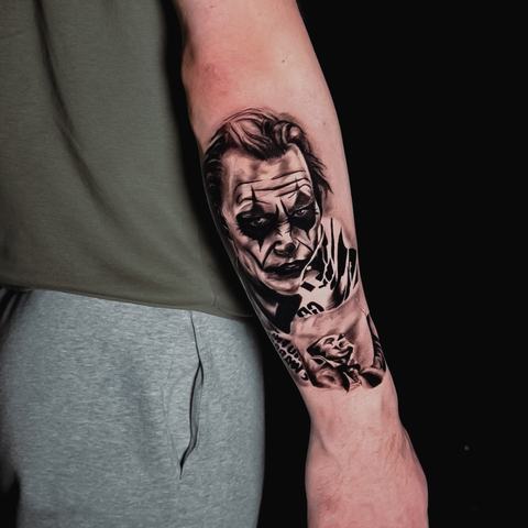 A realistic Joker portrait on the forearm with dark facial details and card-inspired imagery. Strong contrasts enhance the intense and theatrical mood.