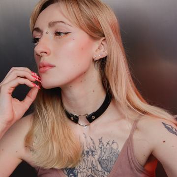 Detail tváre a hrude osoby s viacerými piercingmi v ušiach a na tvári, s chokerom a tetovaním; ilustračné foto k profesionálnemu piercingu v Prešove – VEAN TATTOO.