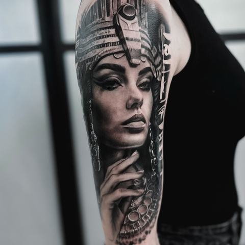 A realistic Egyptian queen tattoo with an ornate headdress and refined facial details. Smooth black-and-grey shading gives the portrait depth and elegance.